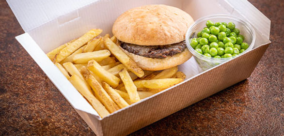 Beef burger and chips with peas in a takeaway box