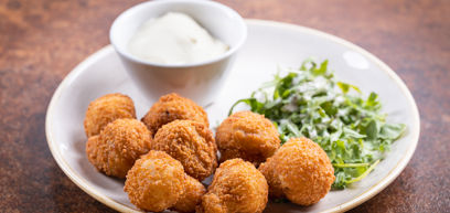 Chicken nuggets served on a plate with salad and a dipping sauce 