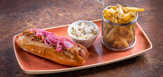 Pulled Pork Dog with grilled hot dog sausage, pulled pork, sweet red onion pickle and Monterey Jack cheese. Served with skin on fries.