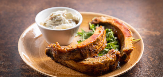 Pork ribs on a plate with salad served with coleslaw