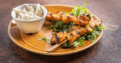 Two chicken skewers and coleslaw on a plate